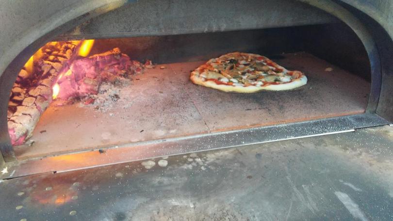 Vegetable pizza with mushrooms and artichokes in a brick pizza oven